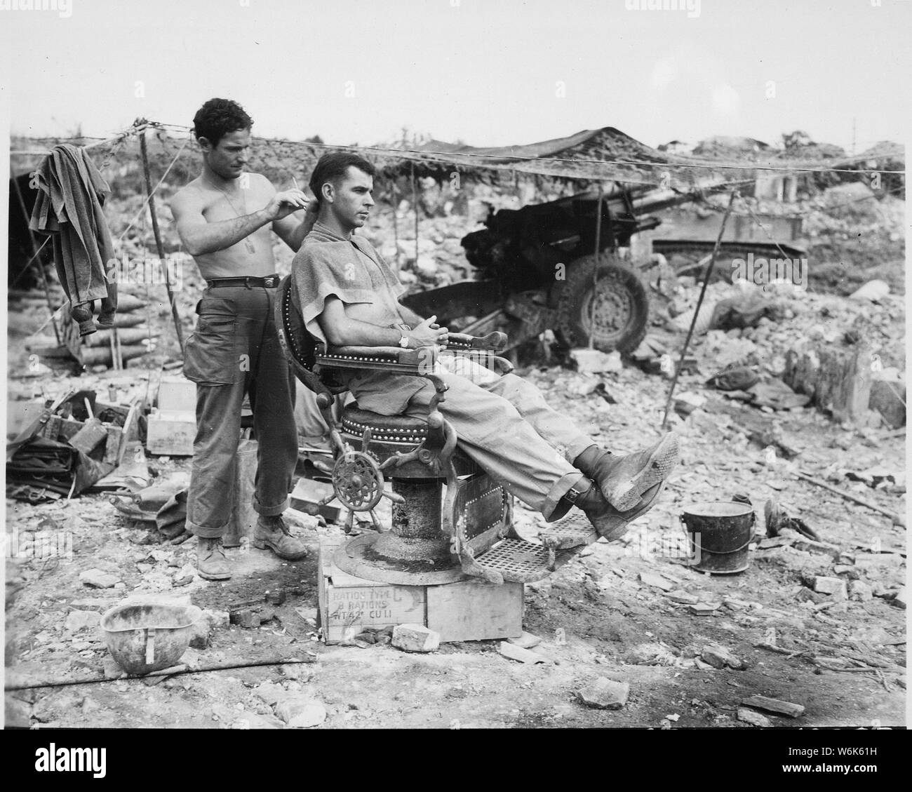 Privato di prima classe Troy Dixon, Leadhill, Arkansas, utilizza un giapponese sedia barbiere per tagliare i capelli del sergente John Anderson, Anita, Pennsylvania entrambi gli uomini sono membri del 363 campo battaglione di artiglieria., situato nei pressi di Shuri. Okinawa, 10 giugno 1945.; Note Generali: Utilizzo di guerra e di conflitto numero 928 quando si ordina una riproduzione o la richiesta di informazioni su questa immagine. Foto Stock