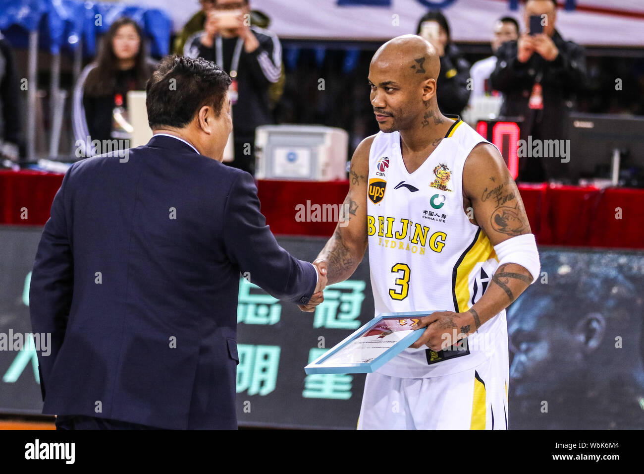 Stephon Marbury di Pechino Flydragon, destra stringe la mano ad un ufficiale cinese come egli riceve un certificato per il dipendente onorario di Pechino en Foto Stock