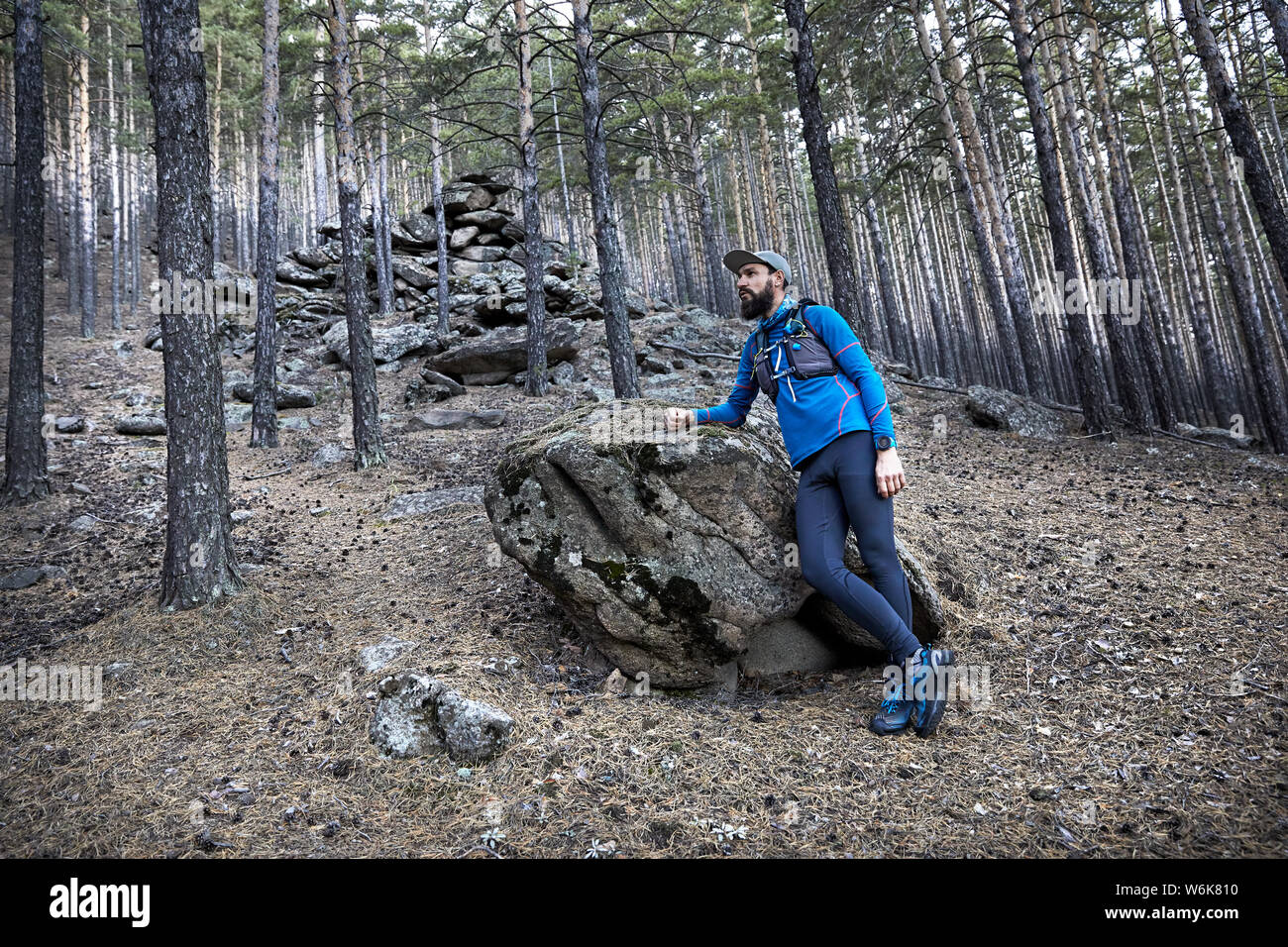 Ritratto di runner atleta con la barba in blu sport costume nei pressi di big stone nella foresta Foto Stock