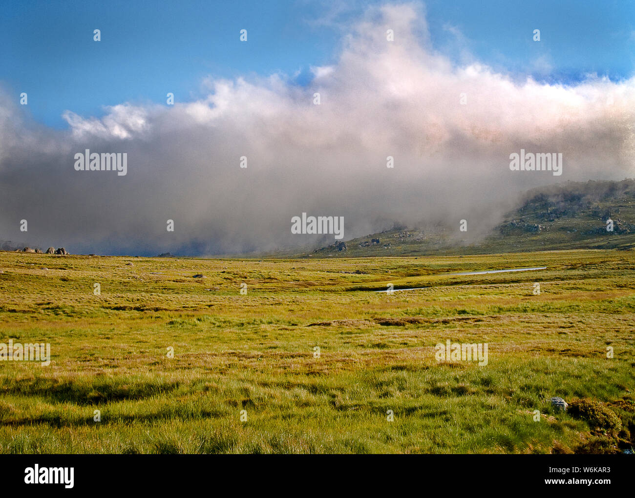Australia: nuvole ampi attraverso un prato alpino, montagne innevate, NSW Foto Stock