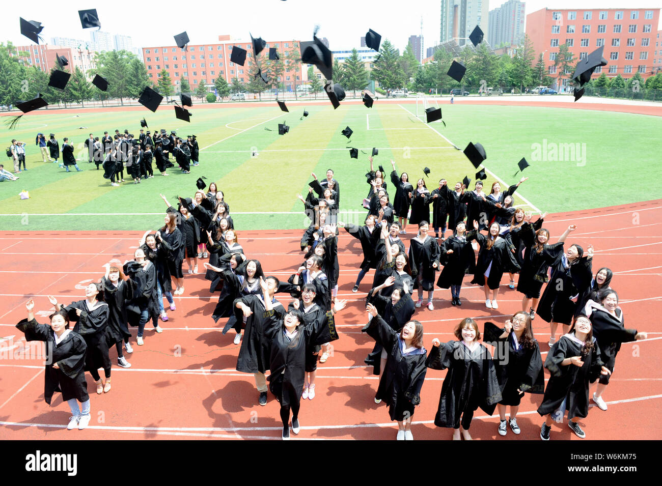 --FILE--laureati cinesi vestito in abiti accademici buttare i loro cappelli in aria durante una graduazione photo shoot a Beihua University nella città di Jilin, Foto Stock