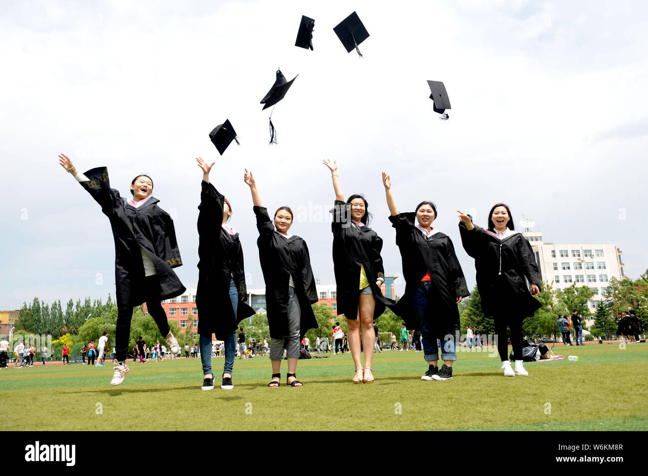 --FILE--laureati cinesi vestito in abiti accademici buttare i loro cappelli in aria durante una graduazione photo shoot a Beihua University nella città di Jilin, Foto Stock