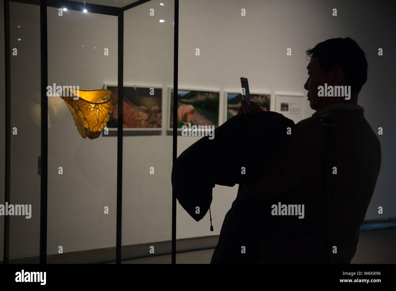 Un visitatore prende le foto del legno illustrazione "Donna che cammina" creata dalla scultore Taiwanese Wu Ching sul display durante l'oro e legno mostra a zh Foto Stock