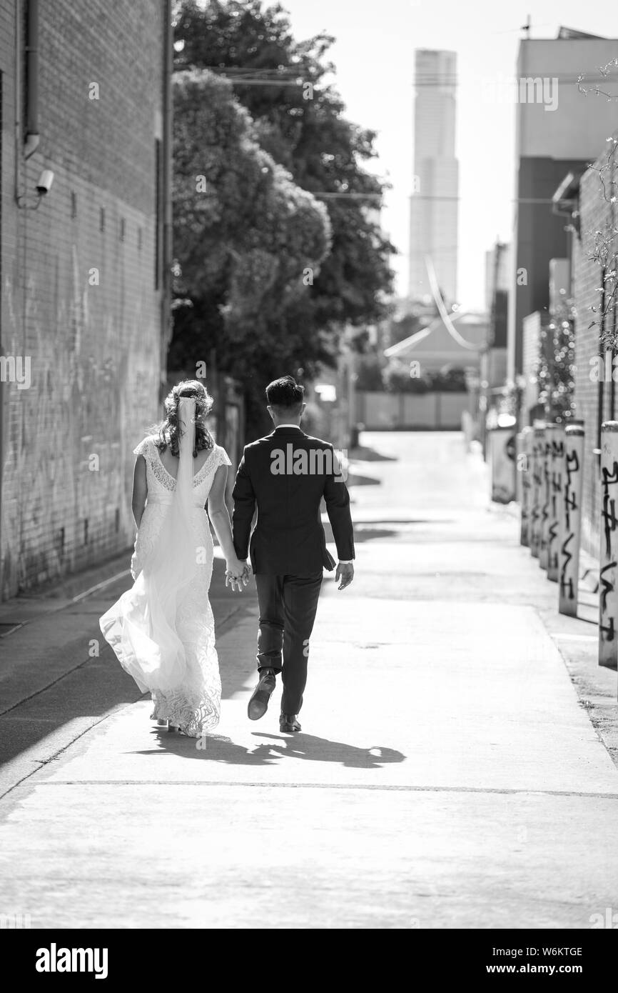 Sposa e lo sposo a piedi giù per la strada sulla loro giorno di nozze Foto Stock