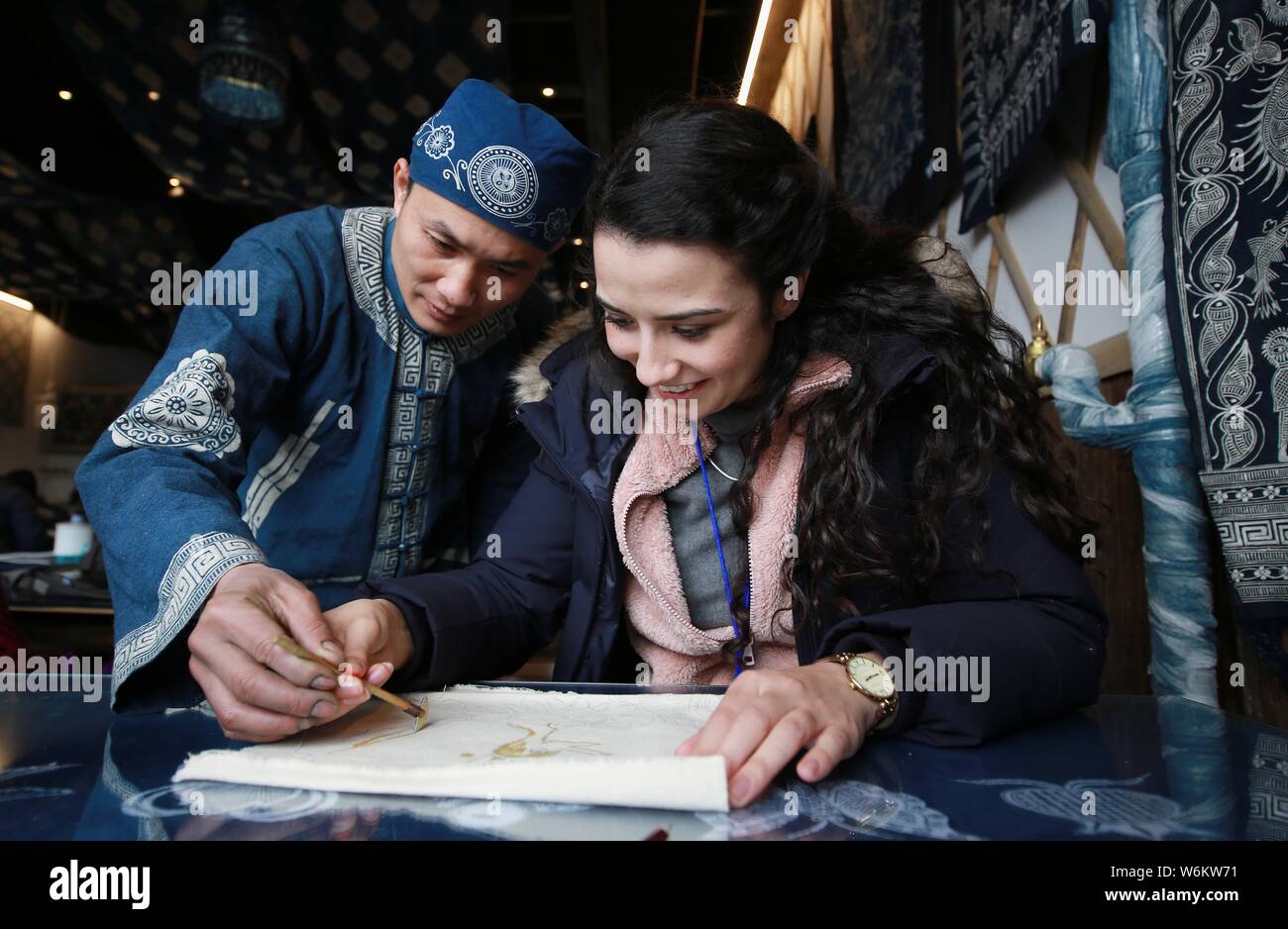 Un overseas student tenta il Miao batik etnici con l aiuto di un artigiano in Danzhai county, Qiandongnan Miao e Dong prefettura autonoma, sud Foto Stock