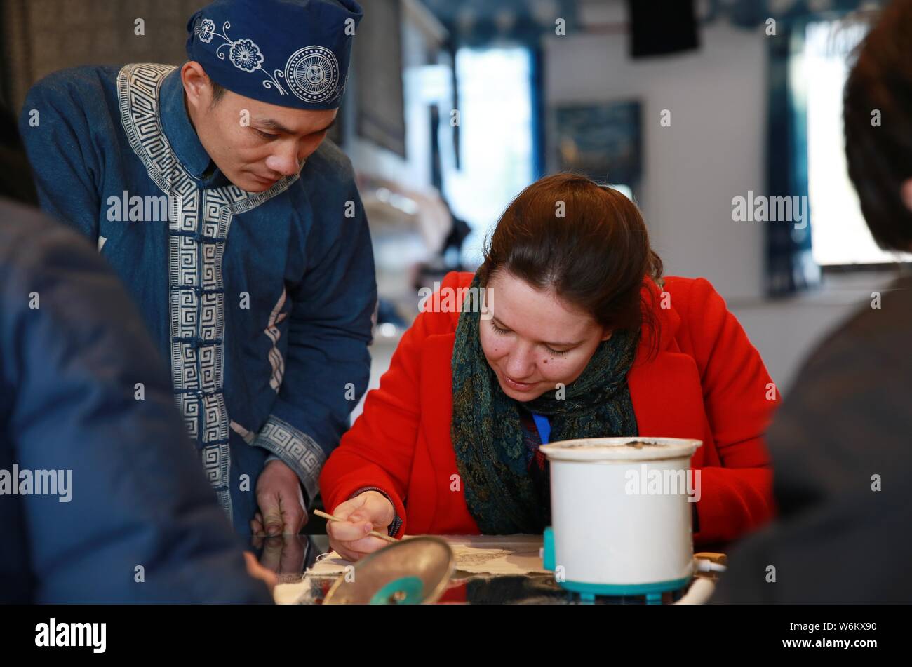 Un overseas student tenta il Miao batik etnici con l aiuto di un artigiano in Danzhai county, Qiandongnan Miao e Dong prefettura autonoma, sud Foto Stock