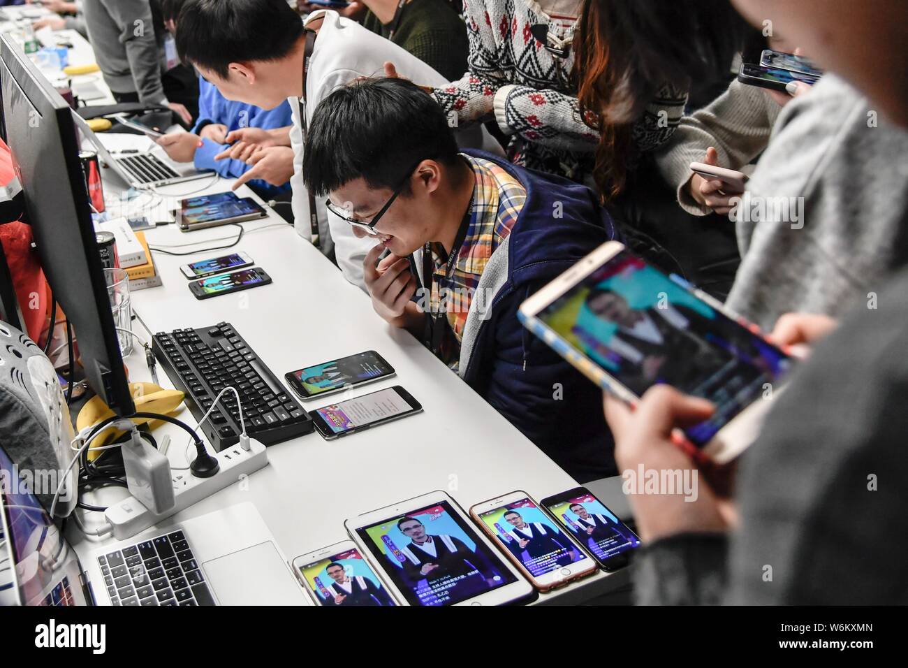Partecipanti cinesi di team fino a utilizzare i loro smartphone per rispondere alle domande del quiz livestreaming piattaforma Yingxiong Baiwan di live streaming video a Foto Stock