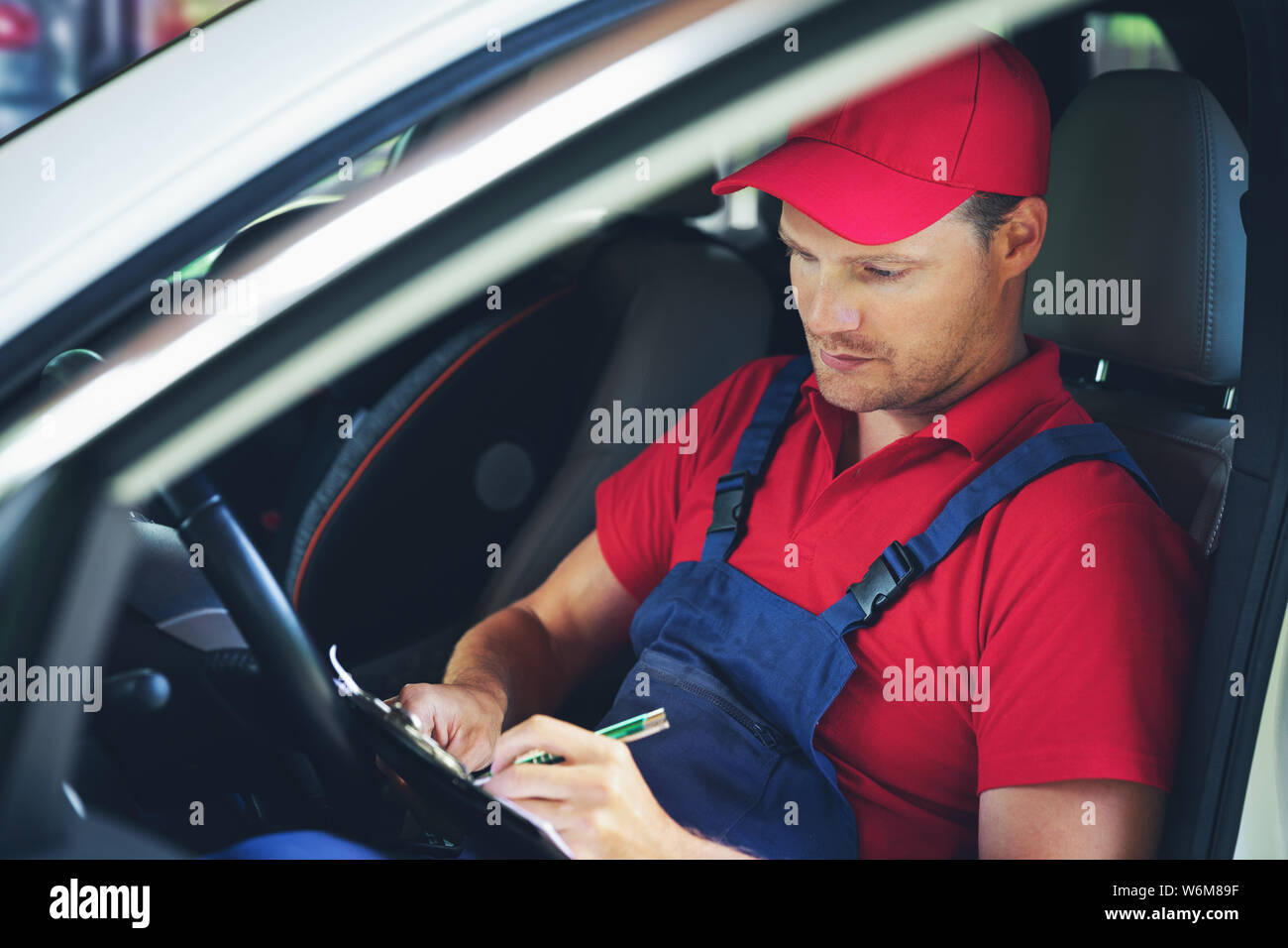 Autofficine seduti all'interno della vettura e la scrittura di documenti di controllo negli appunti Foto Stock