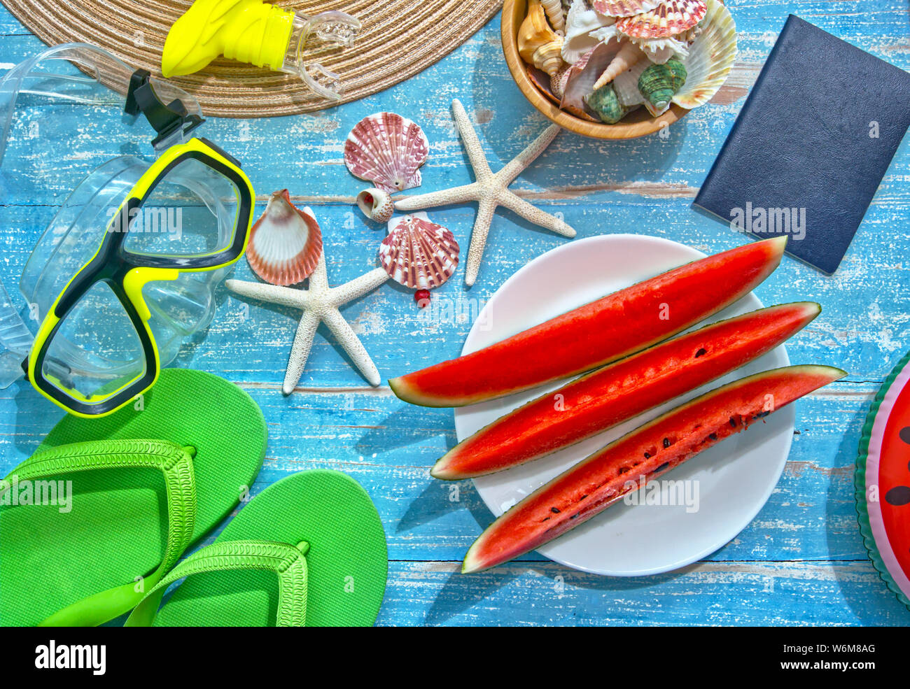 Piatto Topview lay out di anguria a fette decorate con attrezzature subacquee e conchiglia di mare posto su un blu tavolo in legno dal mare,Vacanza Estate concetto. Foto Stock