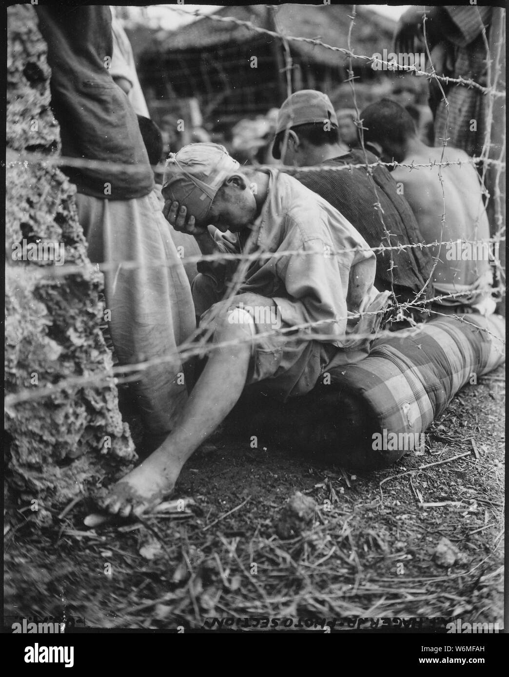 Questo sconsolato giapponese del prigioniero di guerra dejectedly si siede dietro al filo spinato dopo che lui e alcuni 306 altri sono stati catturati nell'arco delle ultime ventiquattro ore della battaglia di Okinawa dalla sesta Divisione Marine. Okinawa, Giugno 1945.; Note Generali: Utilizzo di guerra e di conflitto numero 1307 quando si ordina una riproduzione o la richiesta di informazioni su questa immagine. Foto Stock