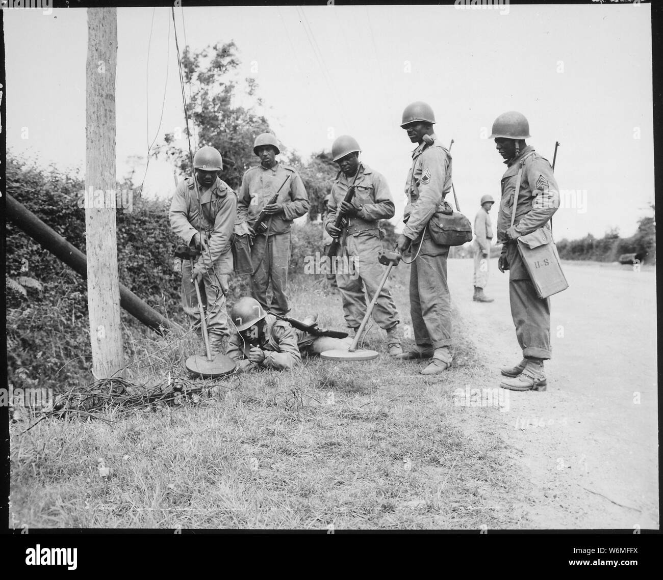Questo rilevatore di mine equipaggio è la dimostrazione di cosa fare prima di andare a lavorare su o intorno ai pali del telefono in Francia., 13/07/1944, campo di applicazione e il contenuto: da sinistra a destra: M/Sgt. Bennie Burns, Sgt. Vincent MacNeill, Sgt. Frank Mack, PFC. Riggles McCutcheon, T/Sgt. John A. Barbee e Sgt. Thomas G. Alexander. Foto Stock