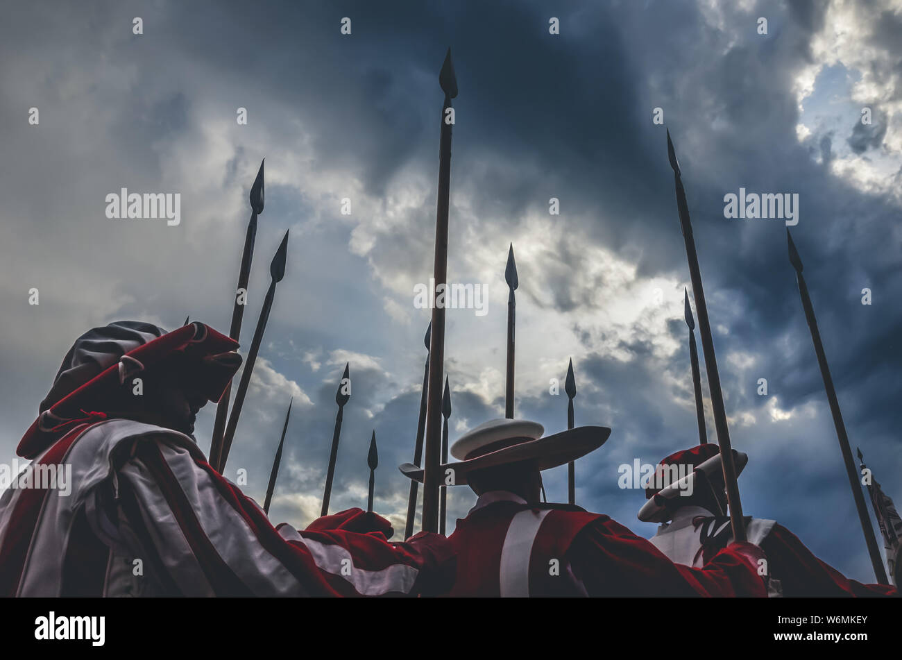 Cavalieri medievali guerrieri azienda lancia pronti per la battaglia. Il bianco e il rosso delle uniformi. Fotografato con drammatica sky prima della tempesta. Lotta armata, concetto, concettuale. Storia, sfondo storico. Foto Stock