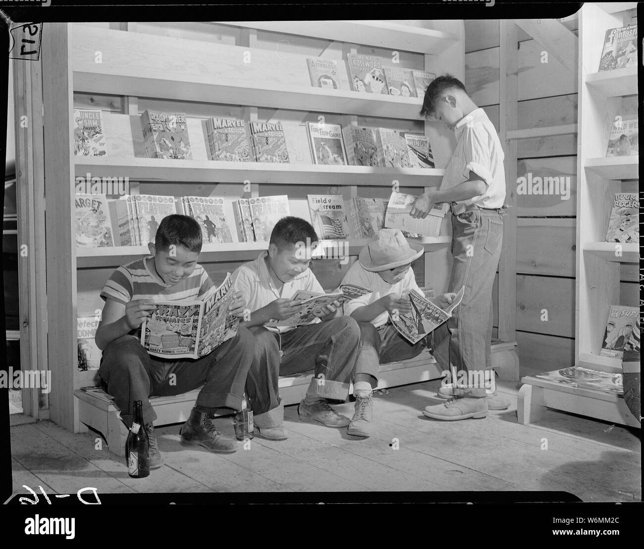 Tule Lake Relocation Center, Newell, California. Quattro piccoli sfollati da Sacramento, California, . . .; Portata e contenuto: tutta la didascalia per questa fotografia si legge: Tule Lake Relocation Center, Newell, California. Quattro piccoli sfollati da Sacramento, California, leggere i fumetti in newstand in questo War Relocation competente centro per sfollati di discesa giapponese. Foto Stock