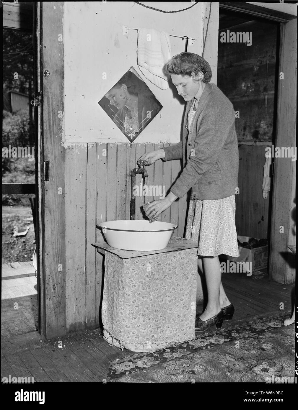Giovane moglie di un minatore il prelievo di acqua al rubinetto nella sua cucina. Questo rubinetto è stato installato da un ex locatario; poche case hanno acqua corrente. Non fumogeno Mullens Coal Company, Mullens miniera, Mullens, Wyoming County, West Virginia. Foto Stock