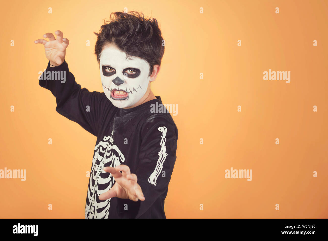 Happy Halloween. divertente bambino in un costume di scheletro di halloween contro lo sfondo arancione Foto Stock