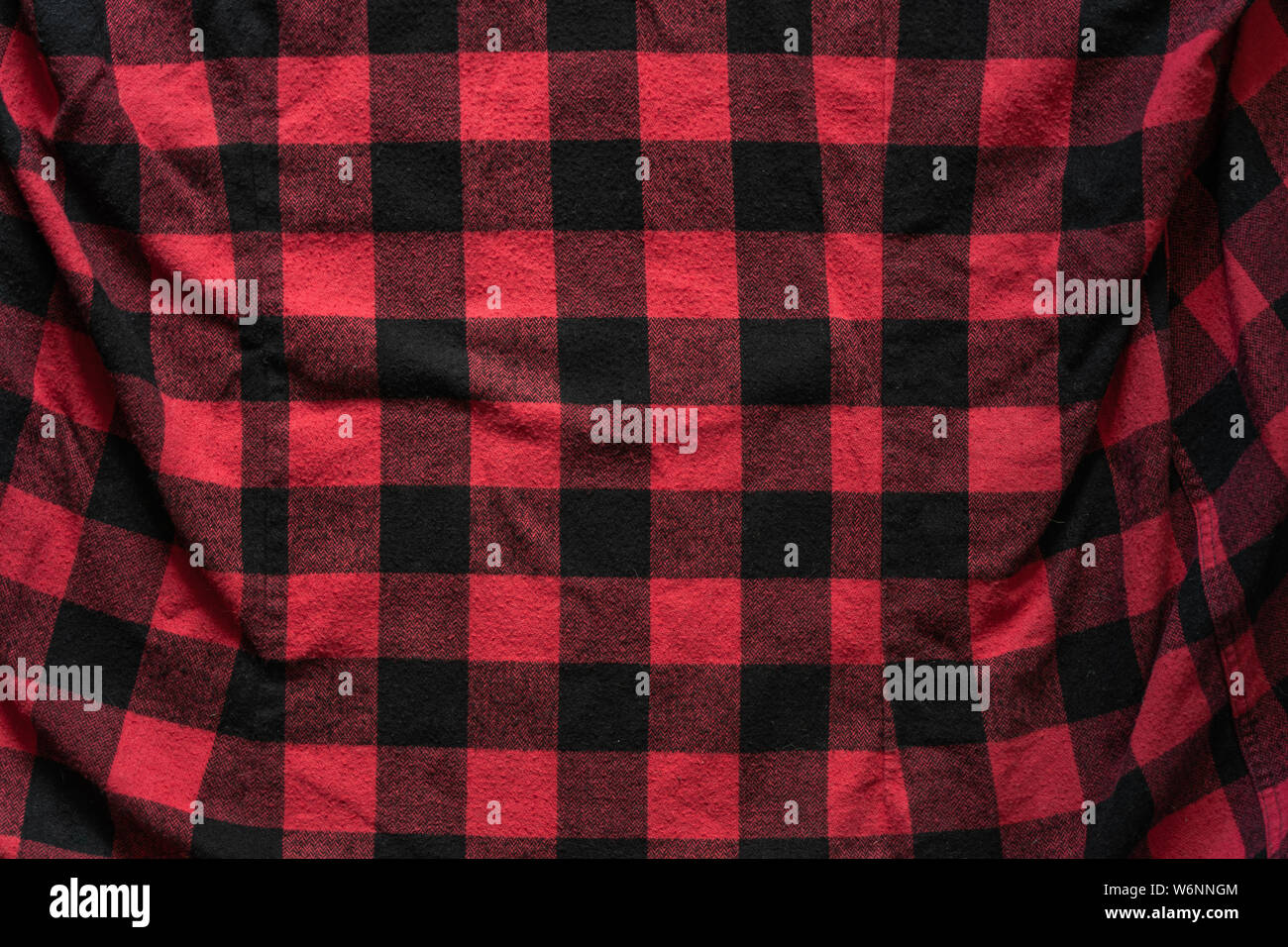 Stropicciata nero e rosso abiti di cella sullo sfondo. Tessuto nero con rosso modello di gabbie. Plaid materiale. Crumpled panno Sfondo bianco Foto Stock