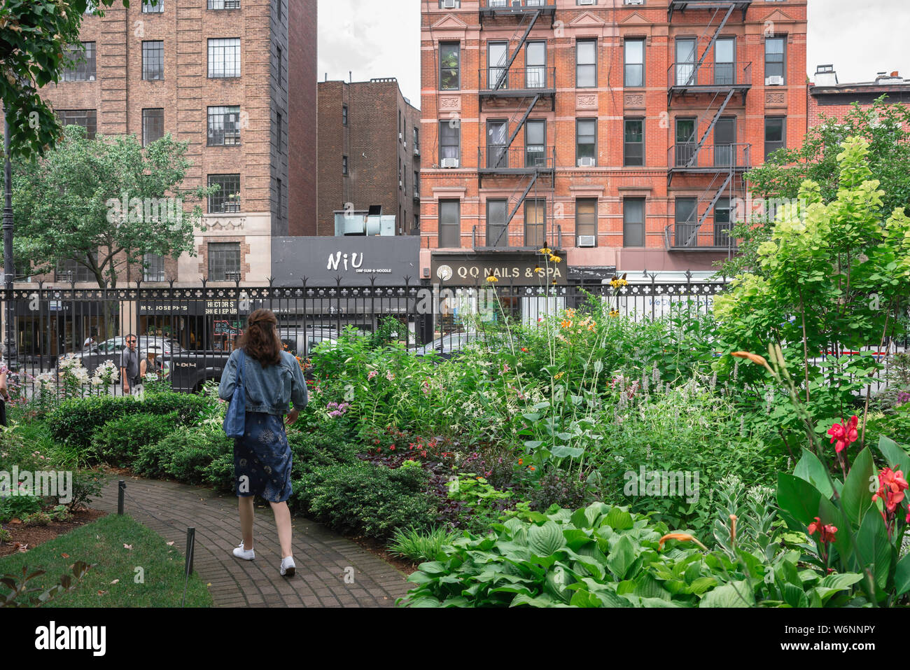 Garden New York, vista posteriore di una donna a piedi attraverso il Jefferson Market Garden in Greenwich Avenue, West Village di New York City, Manhattan STATI UNITI D'AMERICA Foto Stock