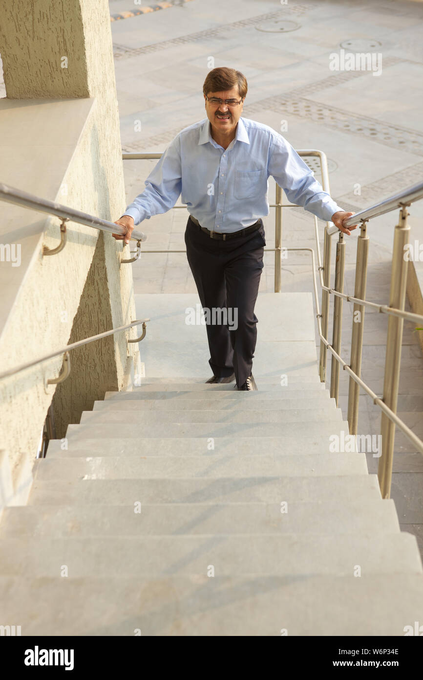 Uomo che lotta per salire le scale Foto Stock