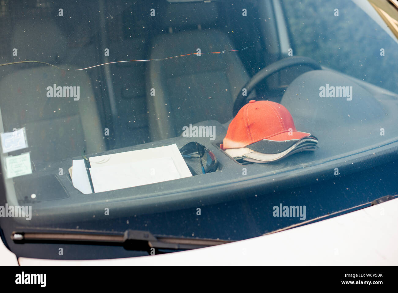 Costruzione van parcheggiato sulla strada con più lavoro cappelli da baseball cap sul cruscotto Foto Stock