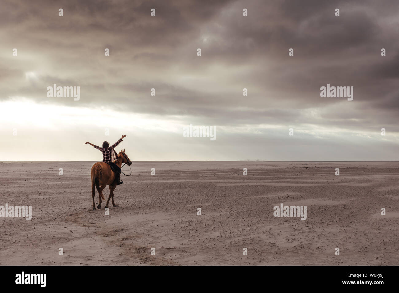 La donna a cavallo sulla spiaggia con le sue mani ampia diffusione. Donna godendo di equitazione lungo la riva del mare in serata. Foto Stock