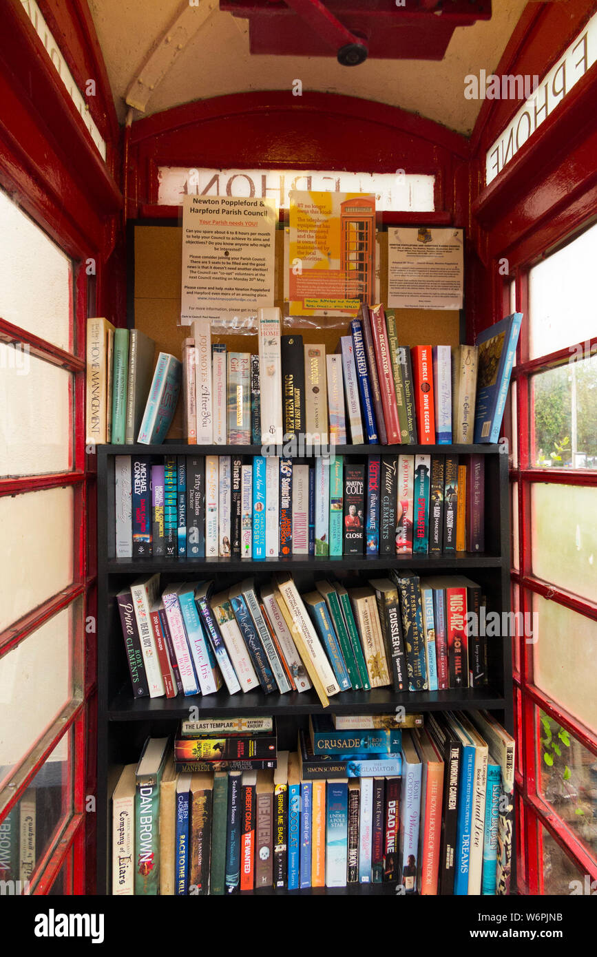 I libri sugli scaffali formando una piccola libreria locale in un vecchio  telefono rosso box / chiosco / call box in Newton Poppleford, Devon.  Inghilterra UK (110 Foto stock - Alamy