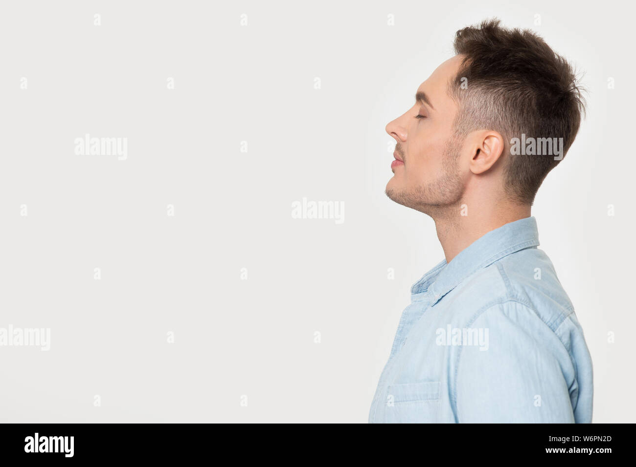 Vista di profilo man standing a parte su grigio di sfondo per studio Foto Stock