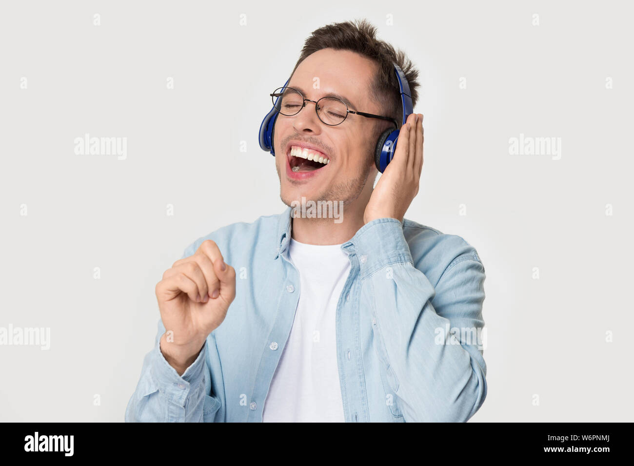 Funny Man millenario chiuso gli occhi indossando le cuffie cantando studio shot Foto Stock
