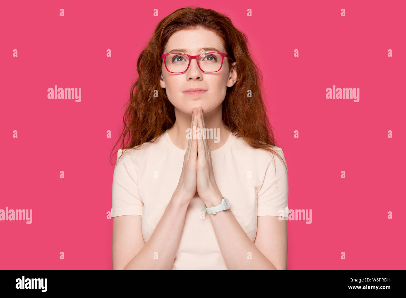 Sincera redhead donna tiene le mani insieme pregando pongono su rosa Foto Stock