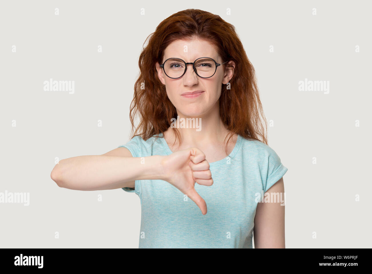 Donna che guarda la telecamera che mostra il pollice verso il basso che esprimono un feedback negativo Foto Stock