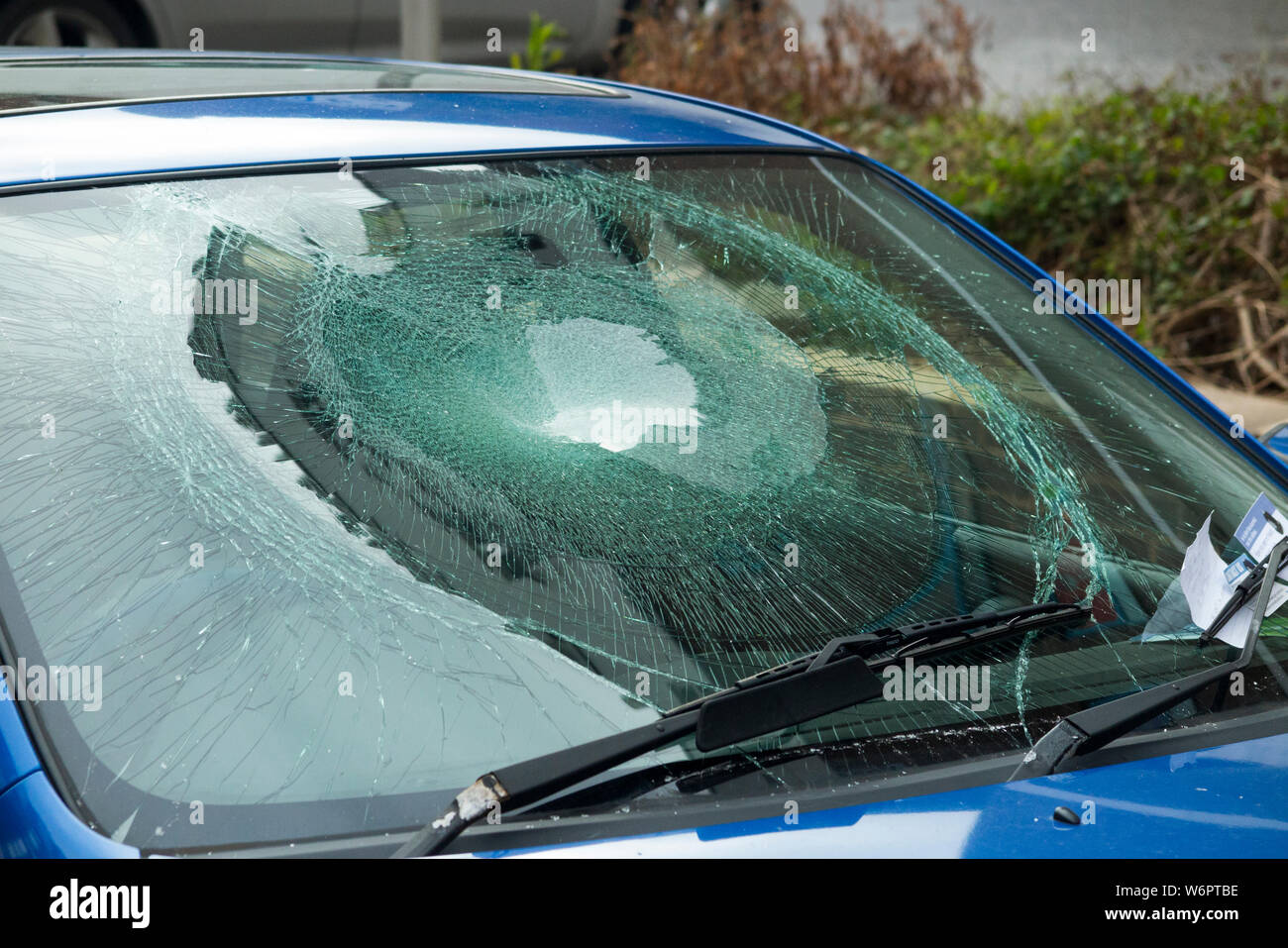 Un parabrezza di automobile che è stata gravemente devastata da un vandalo / atti di vandalismo, indicato da una nota sotto il tergicristallo che dice che è stato causato dai criminali / danni criminali. Regno Unito (110) Foto Stock