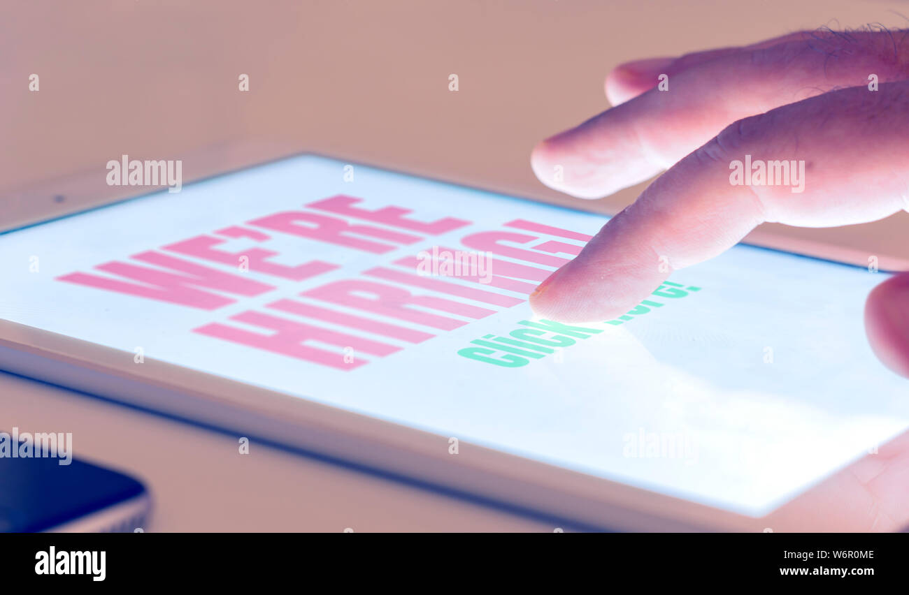 Risposta ad un annuncio di lavoro nuovi assunti attraverso internet con un tablet. Ricerca di lavoro e le opportunità di lavoro Foto Stock