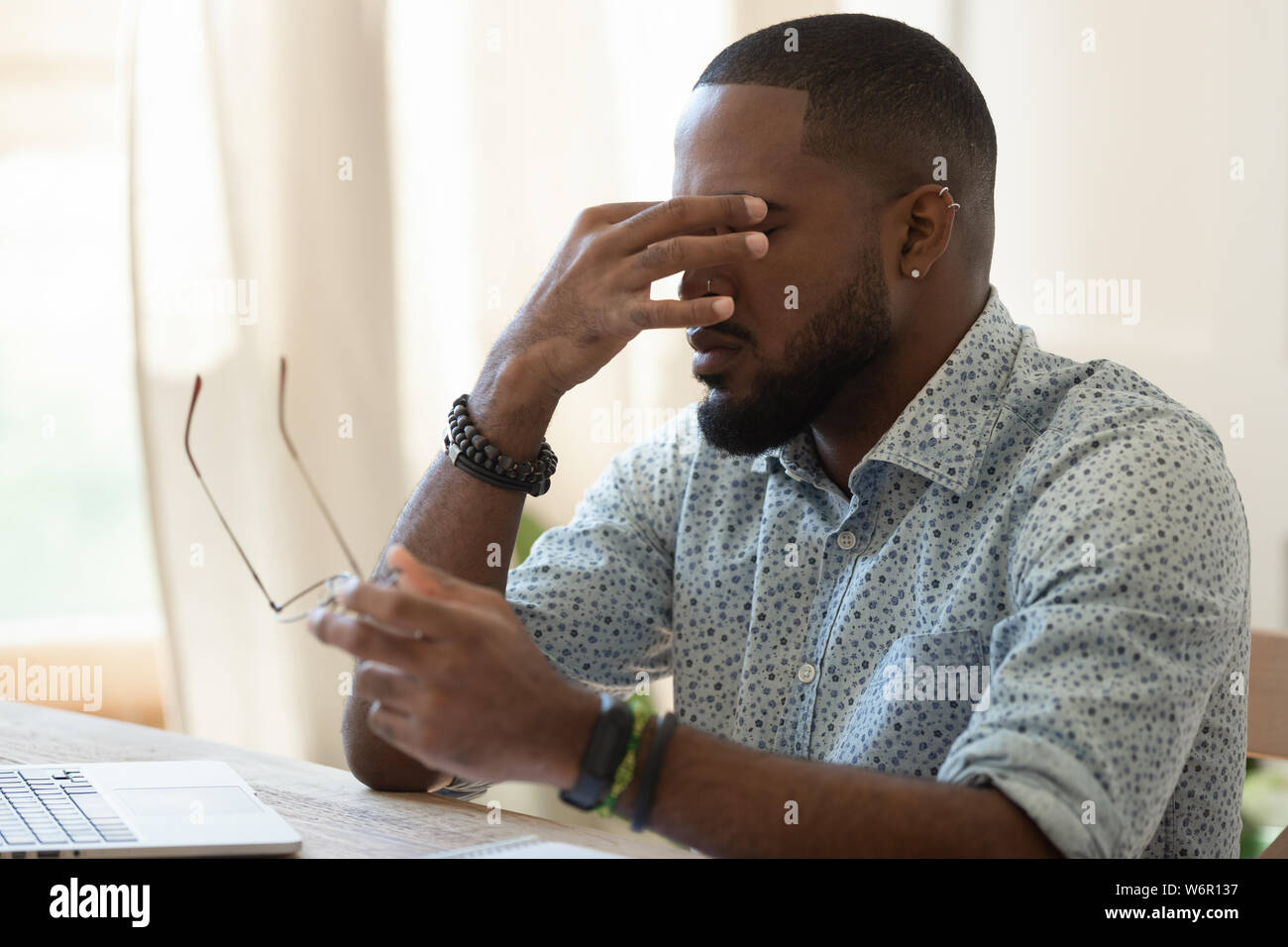 Stanco African American businessman holding bicchieri sensazione di affaticamento della vista Foto Stock