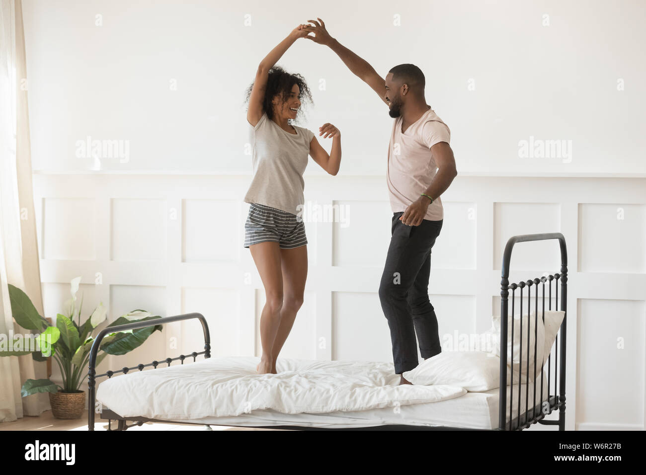 Giovane romantico americano africano giovane indossando pigiami ballando sul letto Foto Stock