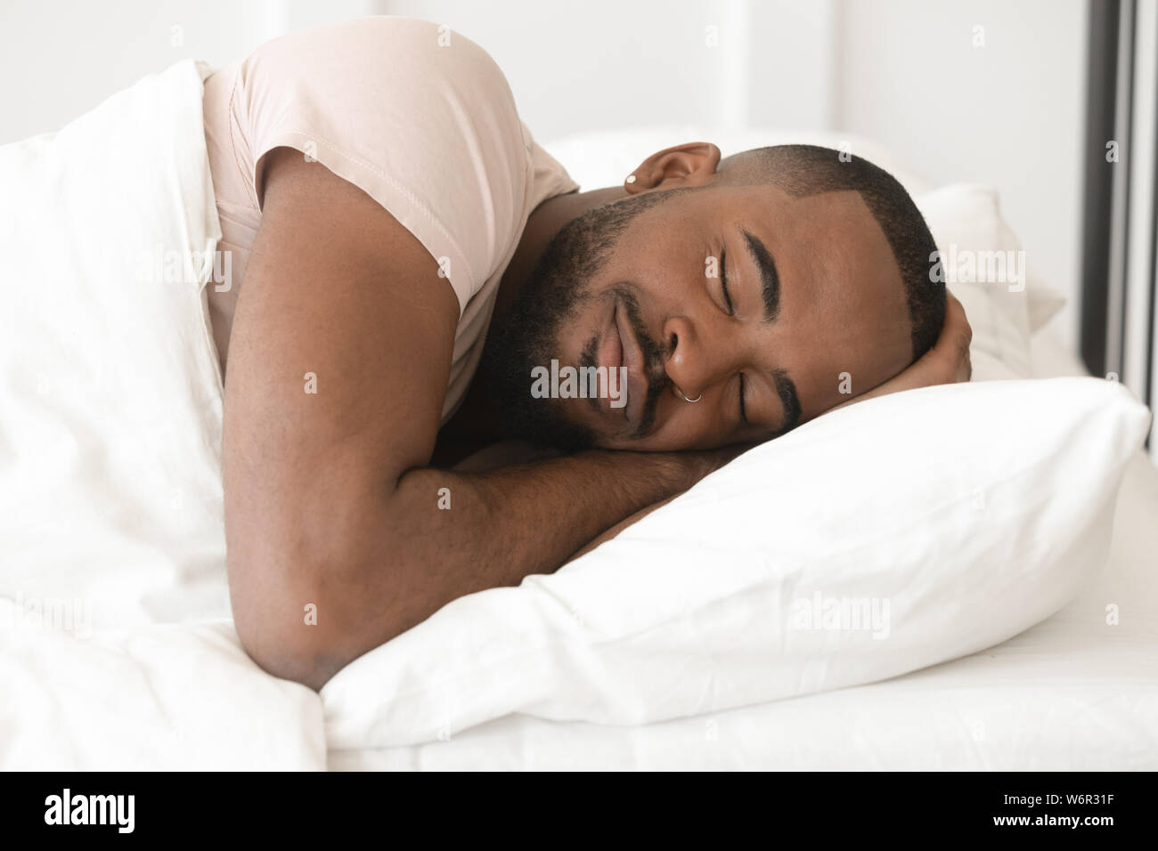 Serena calma giovane uomo nero dormire bene da soli nel letto Foto Stock