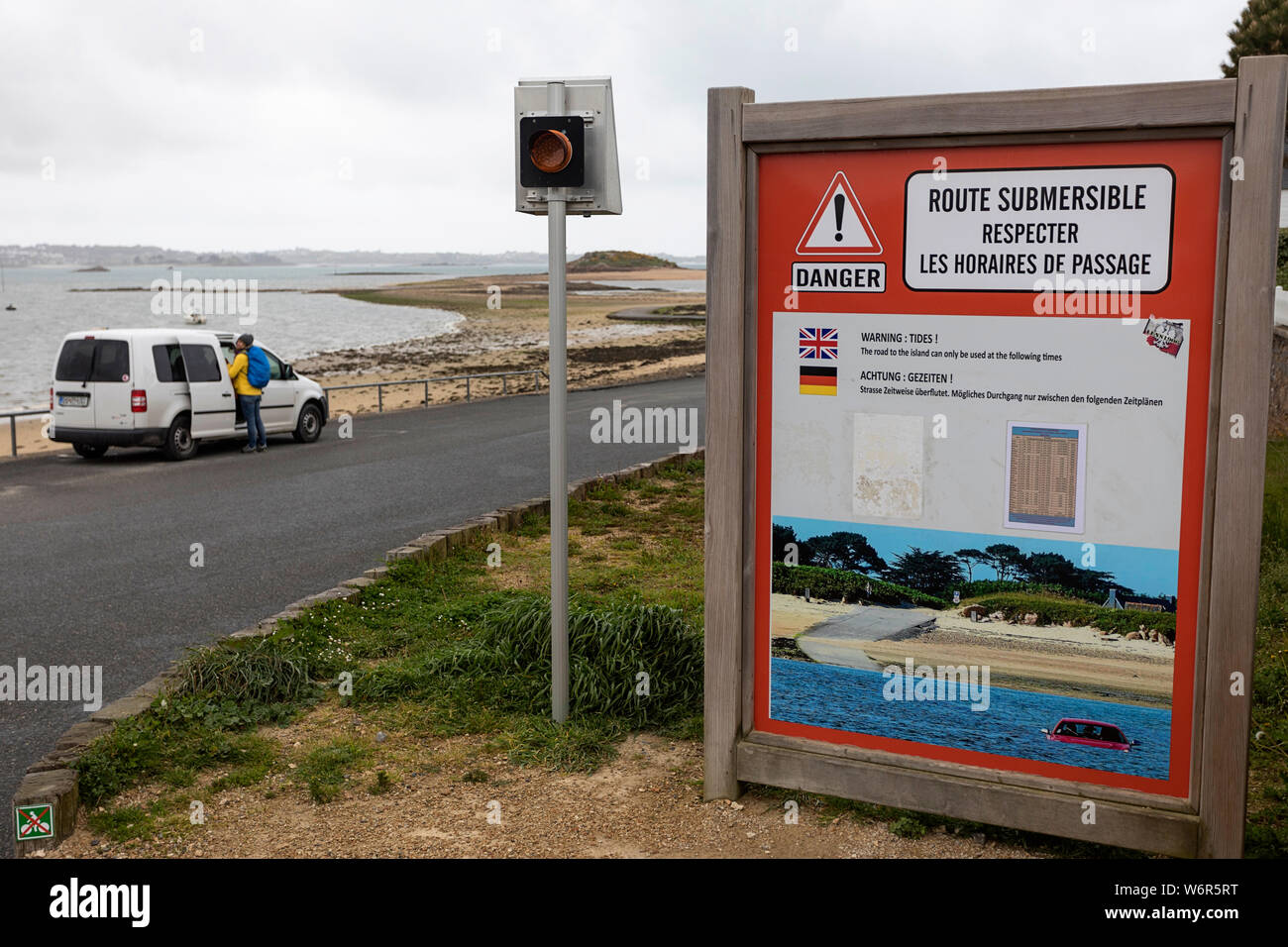 Una vettura parcheggiata nel percorso sommersi in segno di avvertimento che indica che la strada è passibile di fllooding ad alta marea, Bretagna Francia Foto Stock