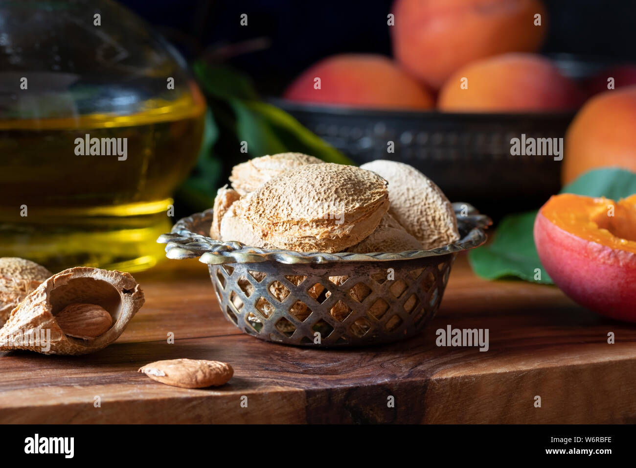 Mature noccioli di albicocca con frutti maturi e olio in background - Fotografia scuro Foto Stock