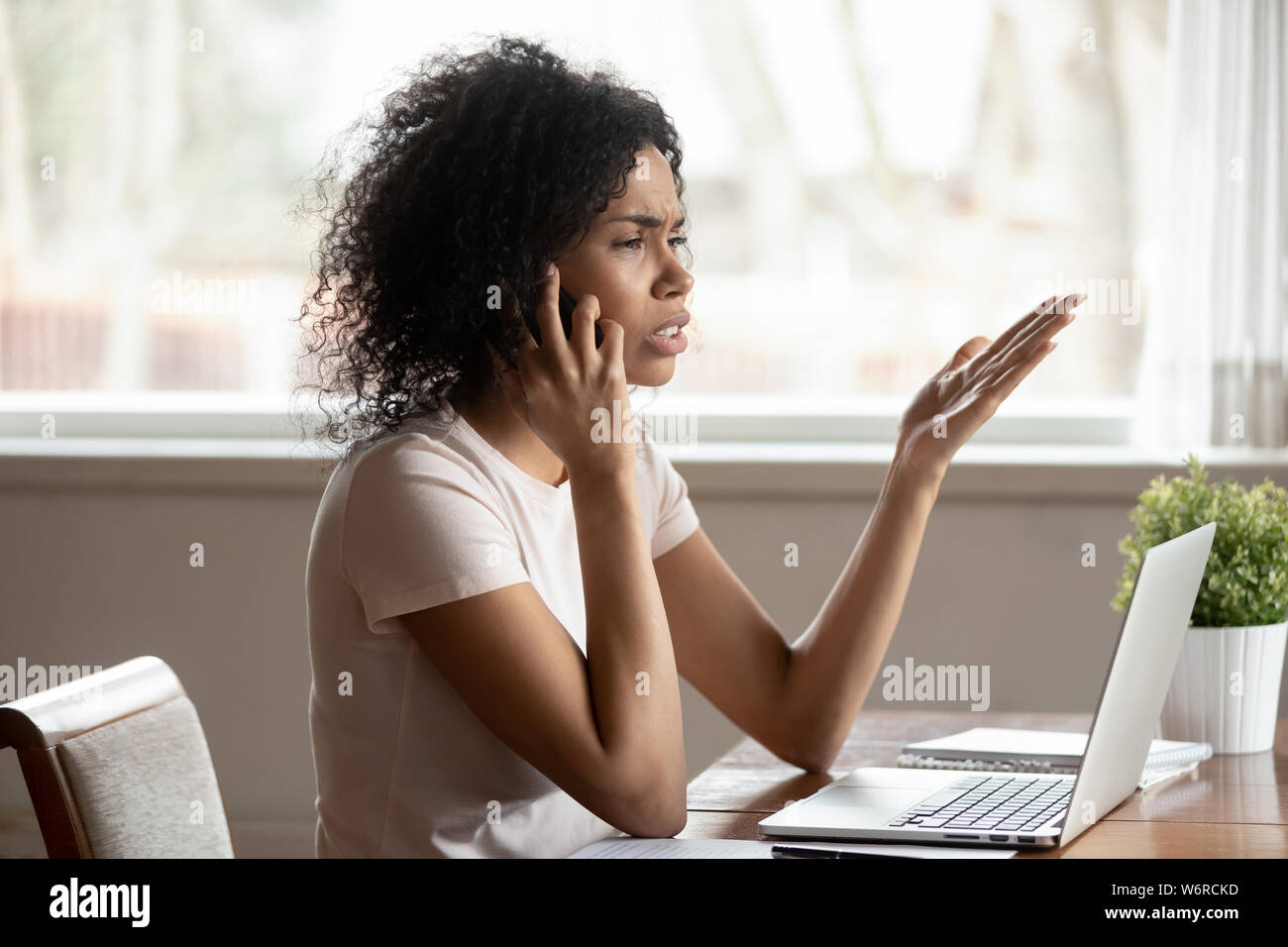 Razza mista donna avente conversazione difficile da telefono cellulare Foto Stock