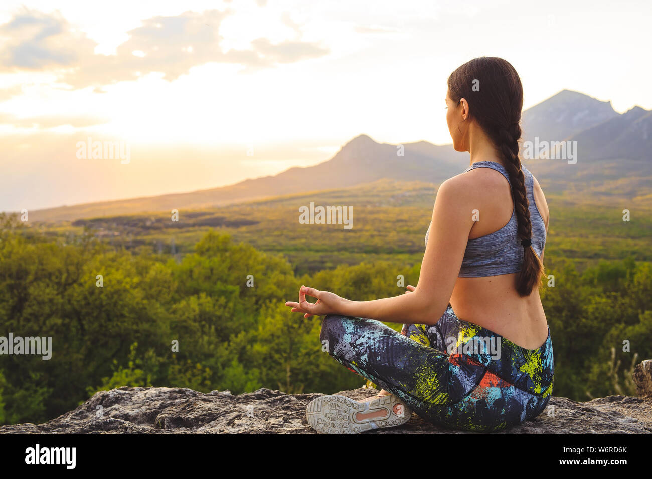 Giovane donna a praticare yoga o pilates al tramonto o l'alba nella splendida località di montagna. Foto Stock