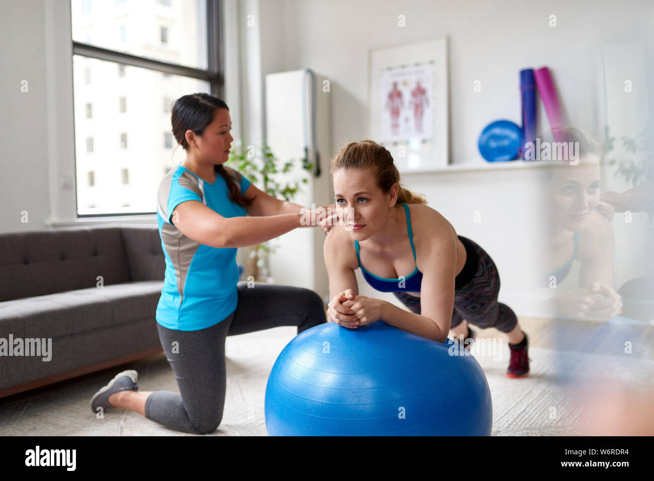 Donna cinese personal trainer durante una sessione di allenamento con un attraente bionda client in un luminoso ufficio medico Foto Stock