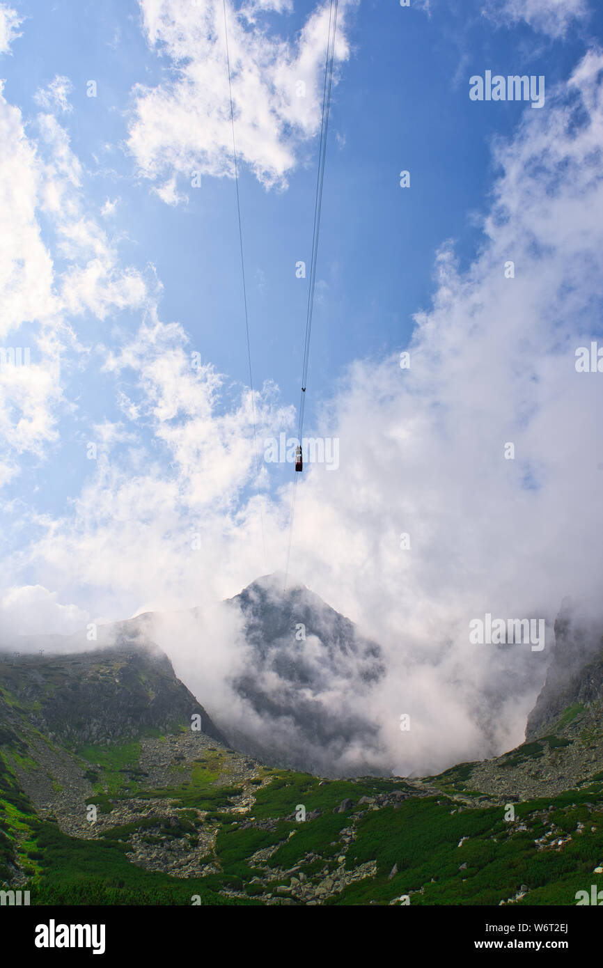 La funivia si innalza attraverso le nuvole sopra le montagne degli alti Tatra in Slovacchia sulla strada per Lomnicky Stit. Foto Stock