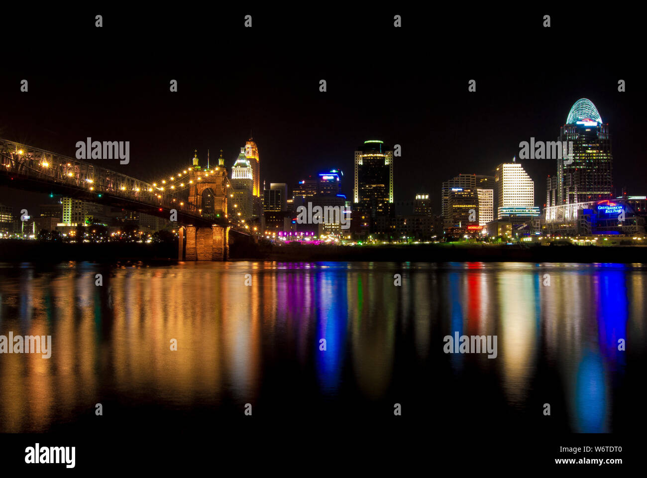 Luci dal centro cittadino di Cincinnati, Ohio, e John A. Roebling Suspension Bridge sono riflessa da una superficie liscia fiume Ohio. Foto Stock