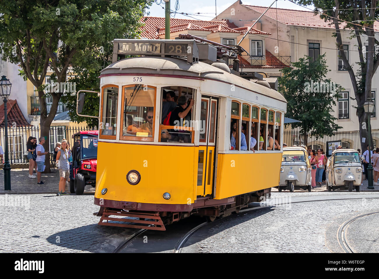 Il famoso tram giallo 28 passando davanti al duomo di Santa Maria a Lisbona, Portogallo Foto Stock