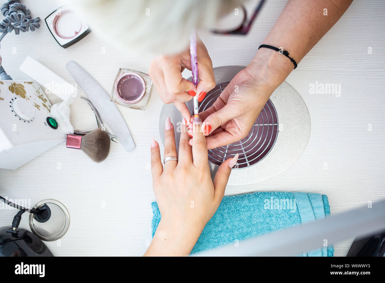 Primo piano della Manicurist applica unghie Gel Polish sul dito. Client ragazza mantiene la mano sul client su asciugamano. Estetista delicatamente i servizi curati Foto Stock