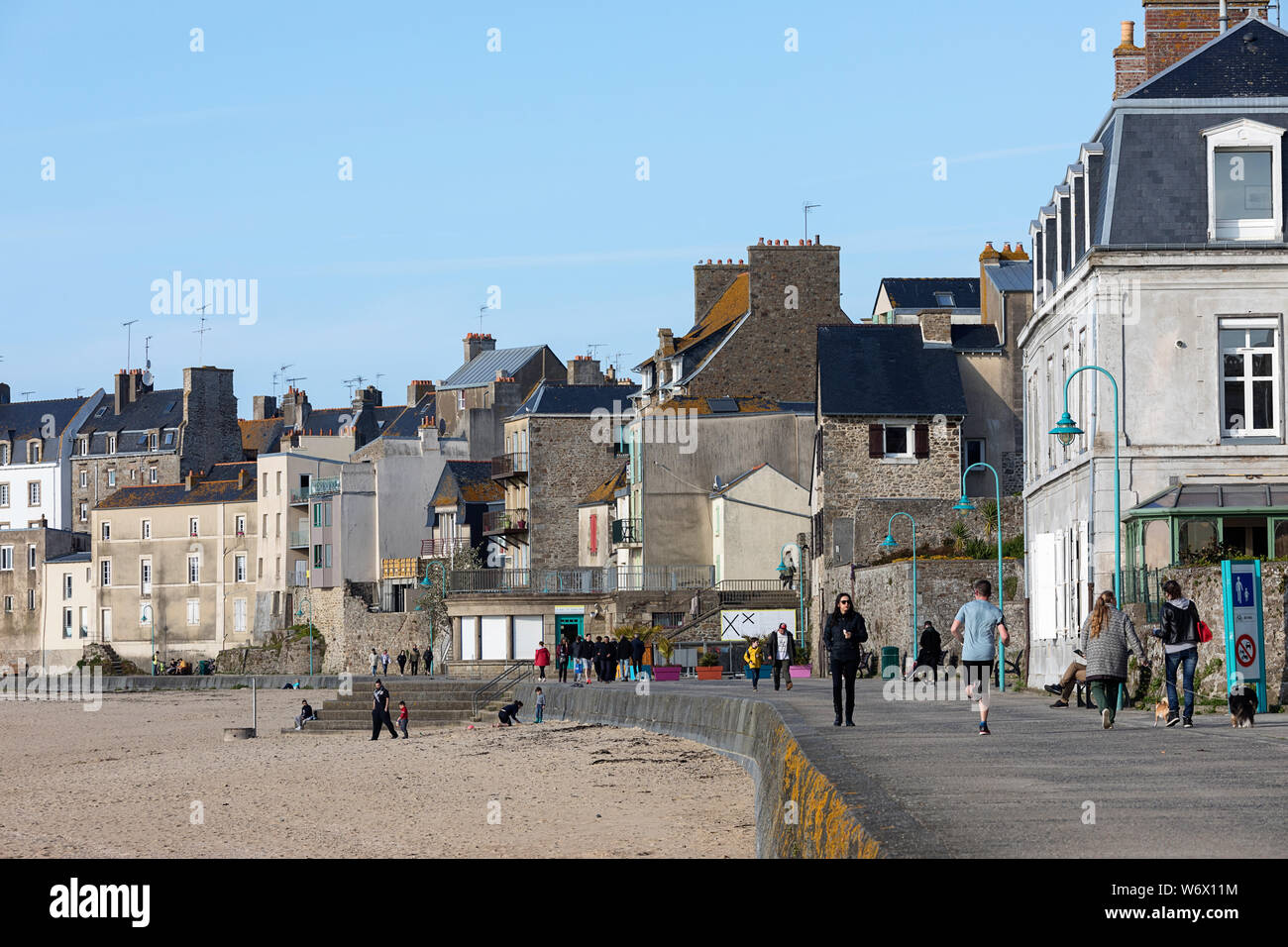 In scena al marciapiede dalla spiaggia di Malo, persone che passeggiano e acceso, Brittany, Francia Foto Stock