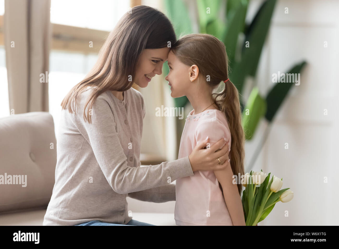 Figlia nascondendo i tulipani toccando permanente di fronte con la madre Foto Stock