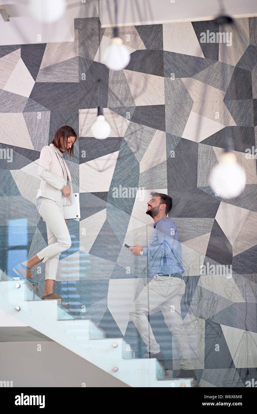 Imprenditore sorridente e imprenditrice a piedi fino alla scaletta Foto Stock