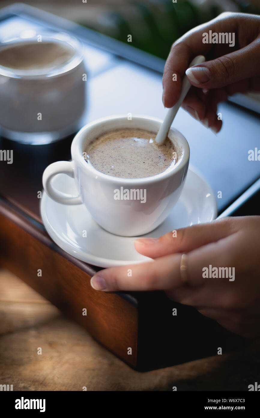 Donna agitare a mano il latte nella tazza di tè Masala Foto Stock