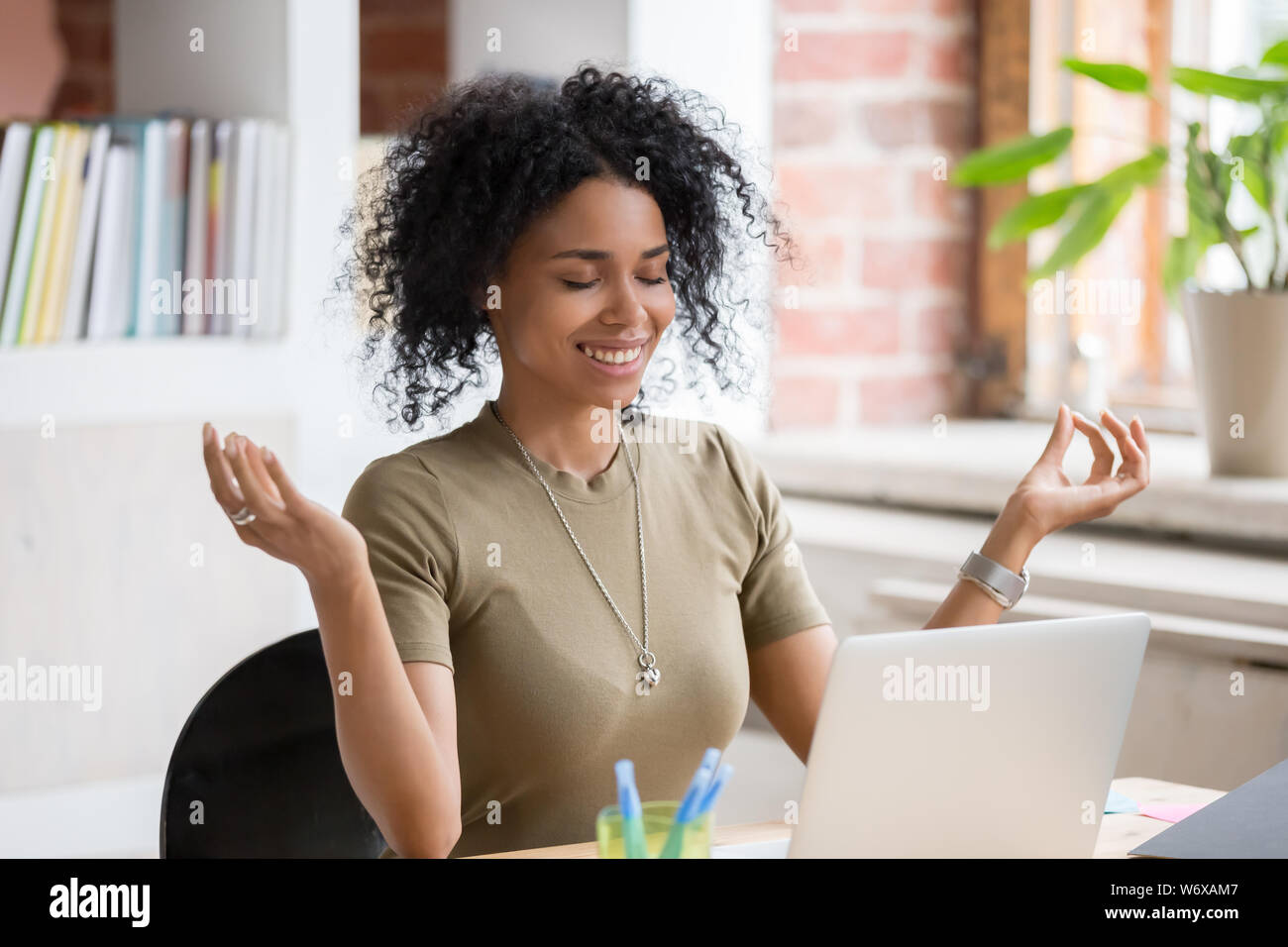 Donna africana seduta a tavola nel posto di lavoro fare esercizi yoga Foto Stock
