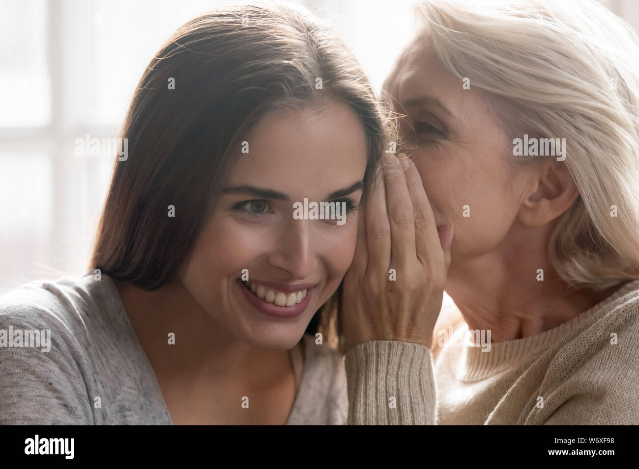 Persone di mezza età madre whispering segreto di cresciuti figlia Foto Stock