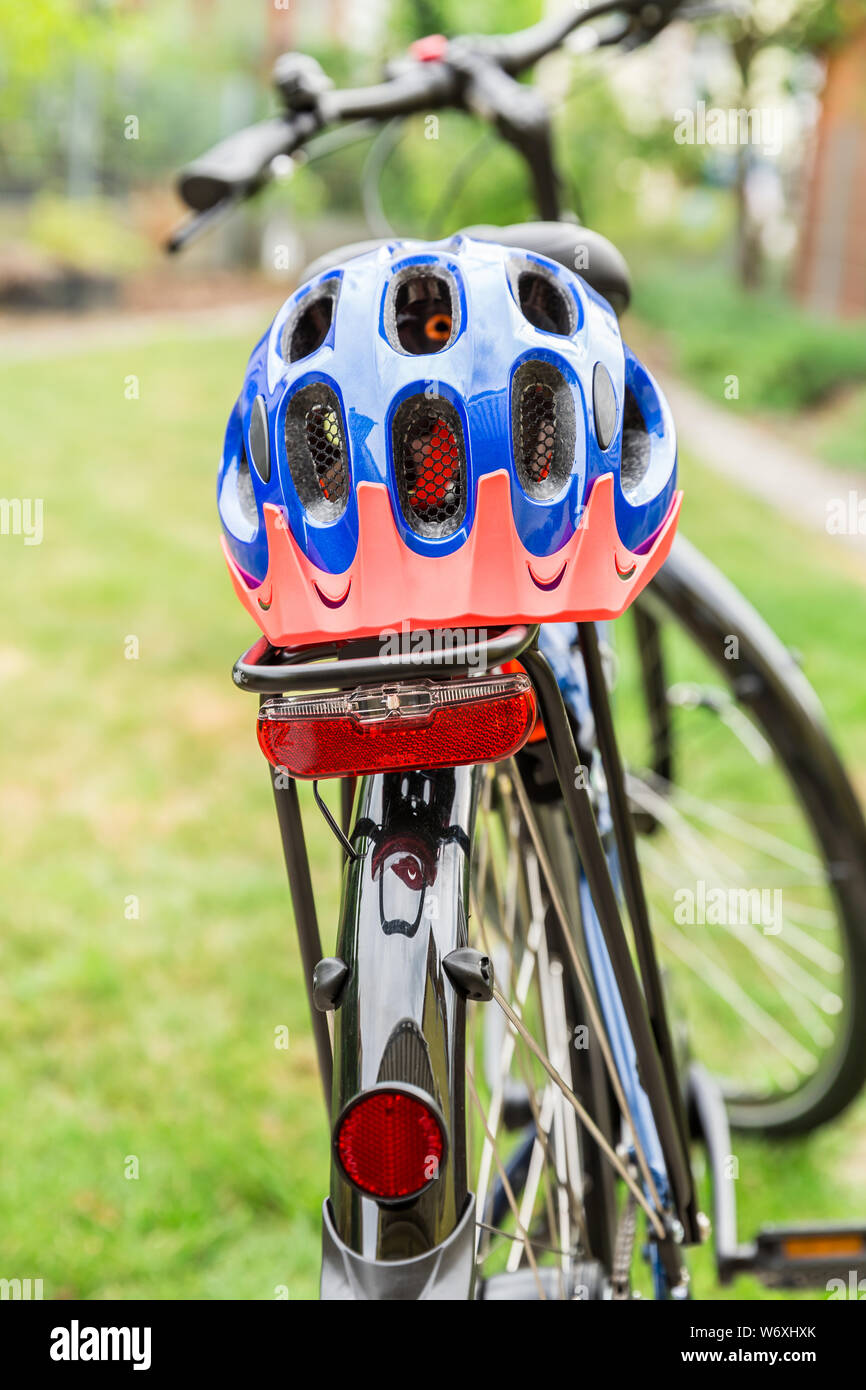 Bicicletta con il casco protettivo disposto sulla cremagliera Foto Stock